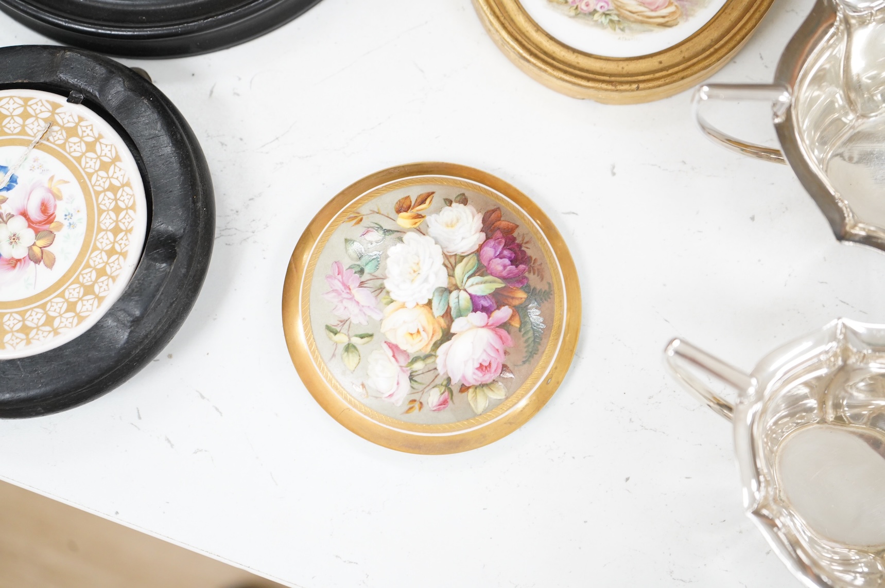 A collection of 19th century porcelain panels, pot lids and plaques to include a pair of hand painted floral lids, Russian lacquered box depicting a lady and a late 19th century Continental brass framed convex oval ename